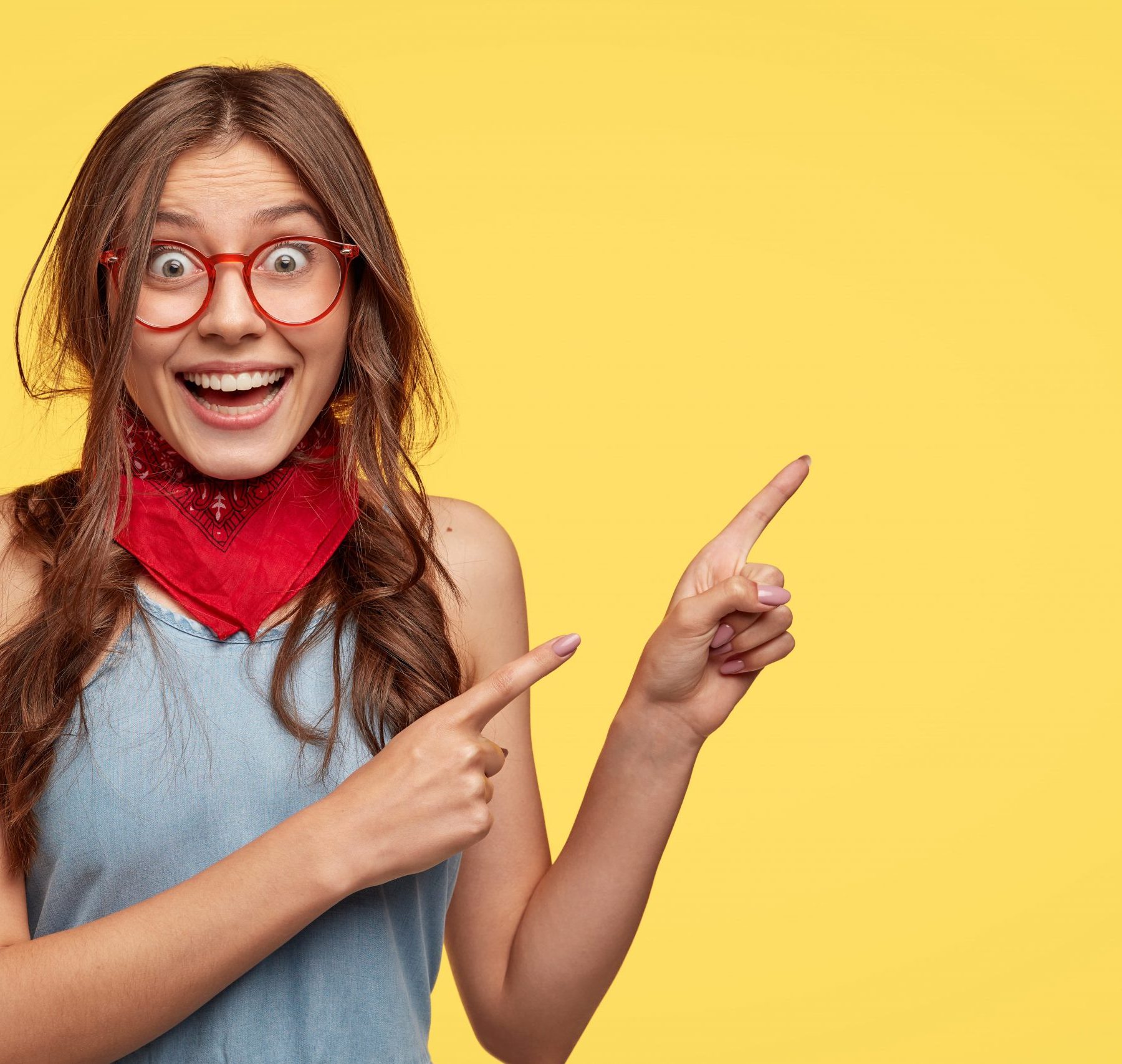 friendly-carefree-female-shop-assistant-points-right-has-board-smile-advertises-new-outfit-with-big-discounts-wears-transparent-glasses-models-against-yellow-wall-with-copy-space-for-slogan (1)