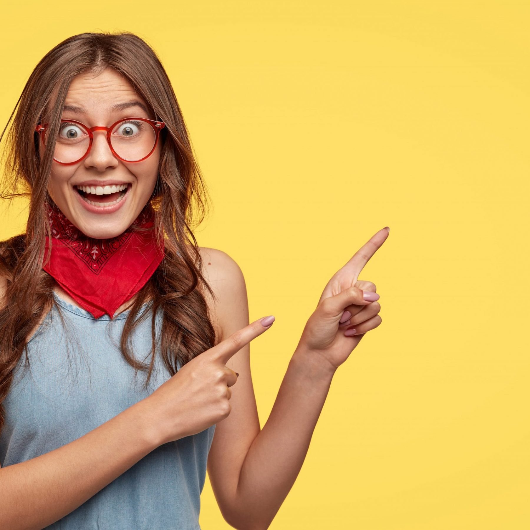 friendly-carefree-female-shop-assistant-points-right-has-board-smile-advertises-new-outfit-with-big-discounts-wears-transparent-glasses-models-against-yellow-wall-with-copy-space-for-slogan (1)